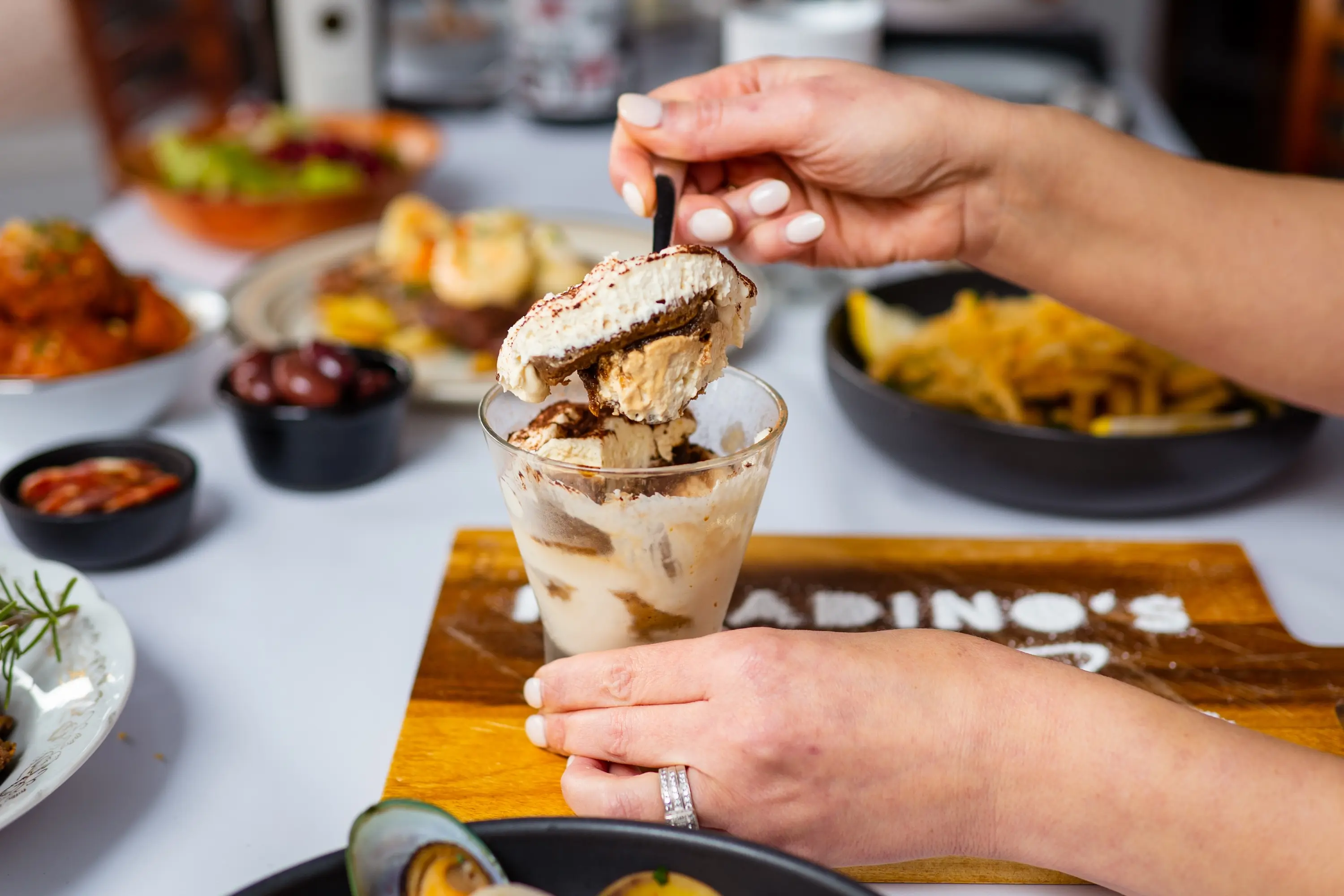 A womans hand scoping icecream out of a glass container.