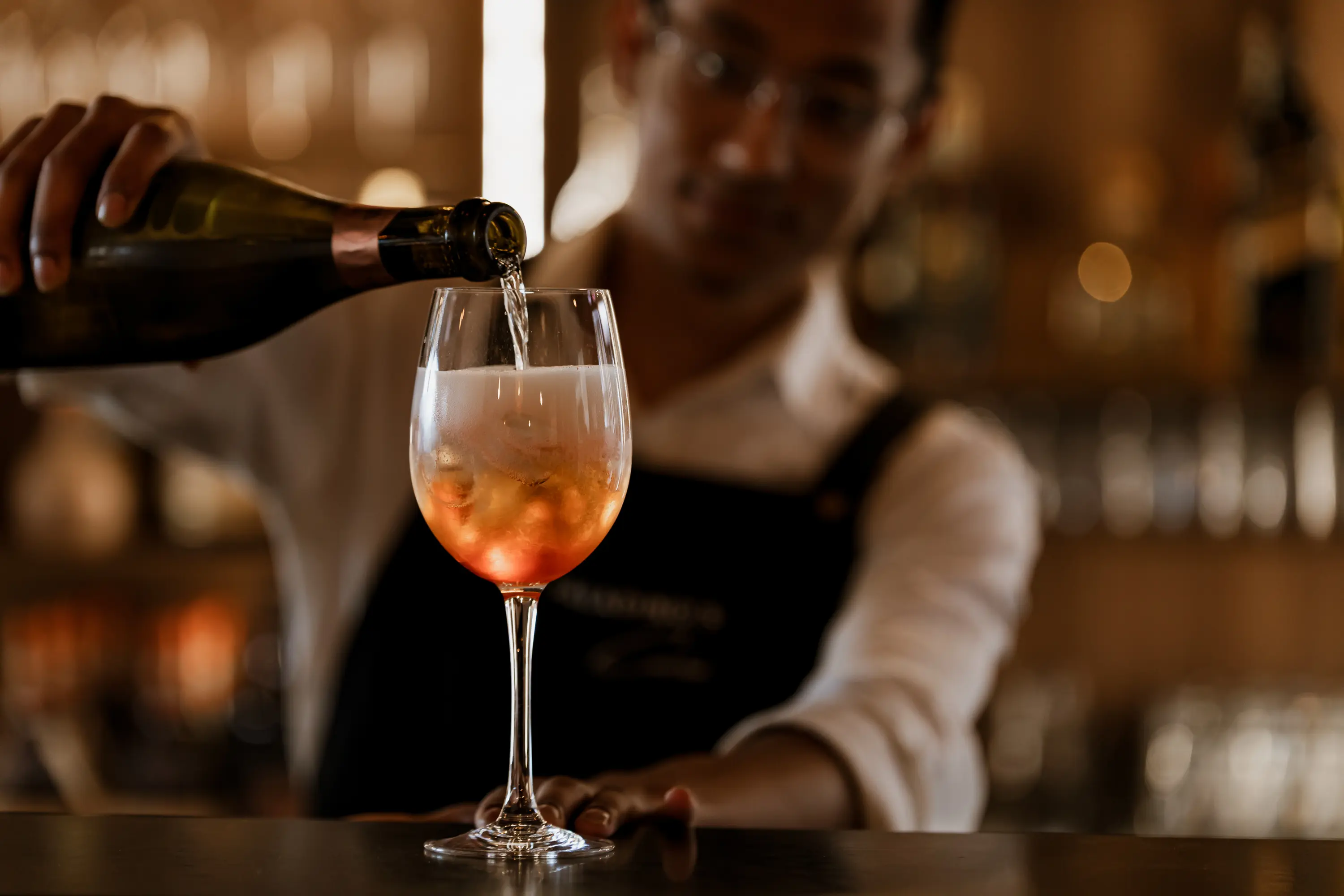 The man at the bar of Paladino's pouring spritz into a glass.