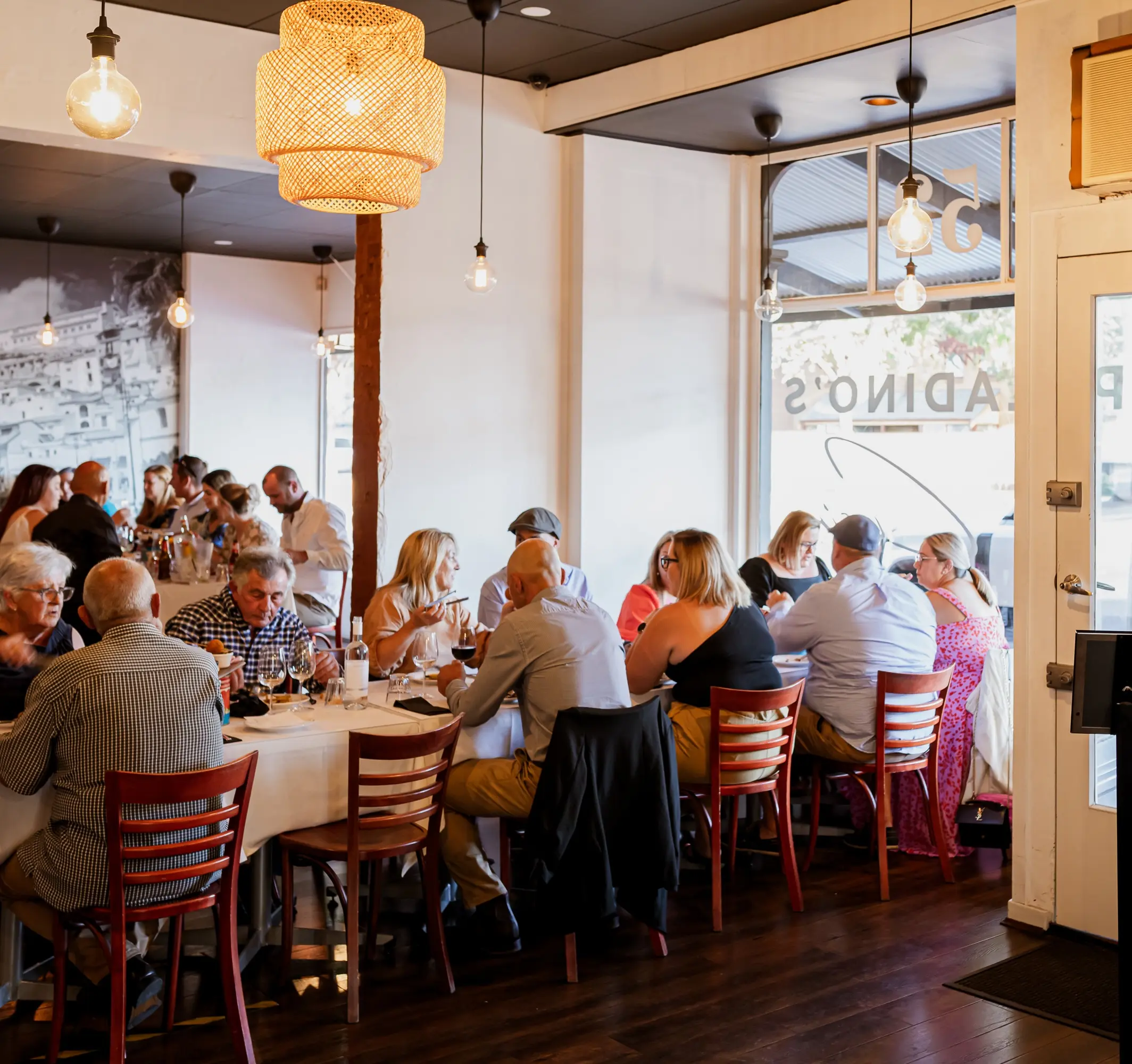 The front room of Paladino's Cucina where people are eating with one another.